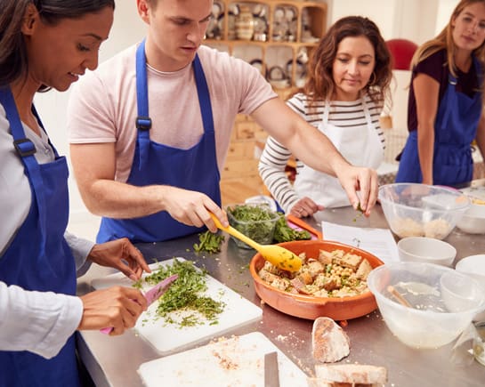 Four people in a kitchen taking a cooking class. 